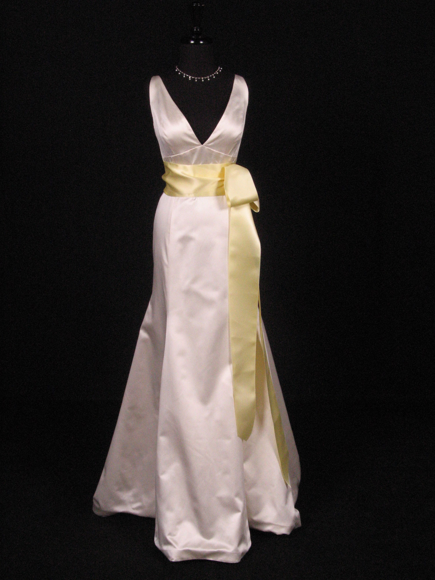 Wedding dress on a form with a buttercream satin ribbon sash