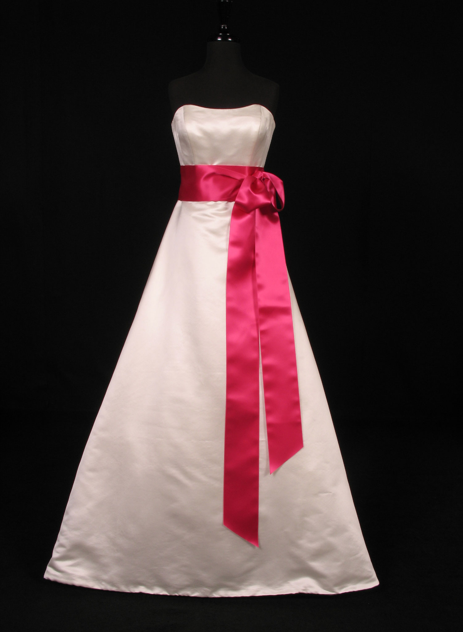Wedding dress on a form with a fuschia satin ribbon sash