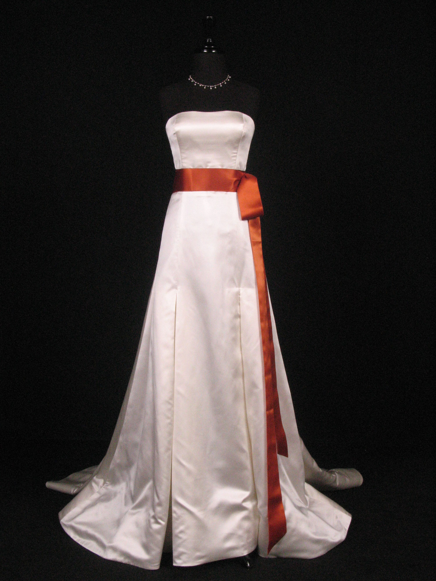Wedding dress on a form with a copper satin ribbon sash